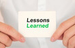 © Sinfebeth - Man's hands take a card with words Lessons learned, finance and business concept.