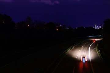 Traffic with motion cars with luminous speed lines and evening sky with landscape of the night city, the concept of a car trip in the dark, speed