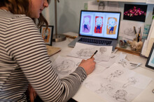 Young Female Artist Looking At Her Caricatures On Laptop