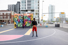 Portrait Confident Young Man On Urban Basketball Court With Mural