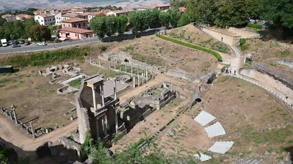 Wall Mural - Volterra, Tuscany, Italy. August 2020. Aerial view of the Roman amphitheater. The tilt movement runs through the entire amphitheater, people inside are visiting it.