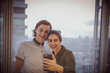 © Tom Merton/Caia Image - Happy young couple taking selfie at highrise window
