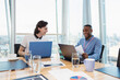 © Robert Daly/Caia Image - Smiling businessmen working at laptops in highrise conference room