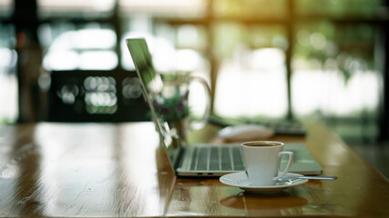 Coffee mug on wooden table with laptop as office background blurred background