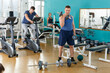 © JackF - Positive young man doing exercises with sports dumbbells at gym