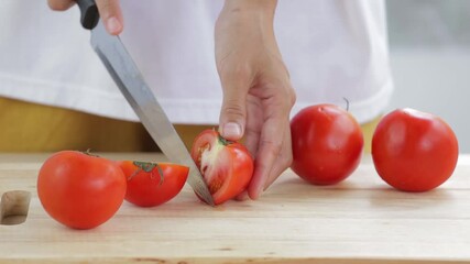 Wall Mural - woman is slicing red tomatoes on wooden cutting board