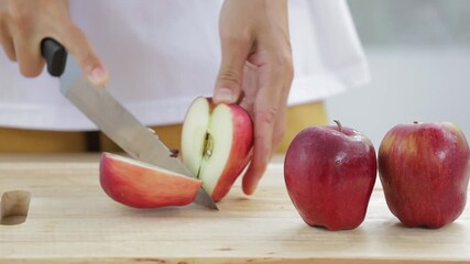 Wall Mural - woman is sliceing red apples on wooden cutting board