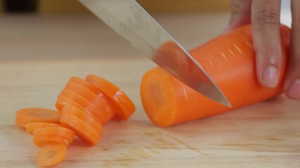 Sticker - woman is slicing fresh carrot on wooden cutting board