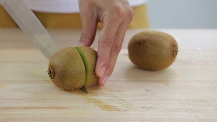 Wall Mural - woman is slicing kiwi fruit  on wooden cutting board