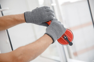 Worker man installs plastic windows and doors with double-glazed white