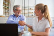 © Mangostar - Businessman meeting and shaking hands with insurance agent at co-working, sitting at open laptop, smiling, discussing agreement. Medium shot,. Handshake or cooperation concept