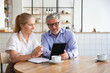 © Mangostar - Positive mature male mentor explaining work details to intern. Business man showing tablet screen to young female colleague. Medium shot, copy space. Communication or teamwork concept