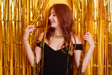 Pretty Female Clubber Being Photographed Among Golden Tinsel, Looking Smiling Aside, Receives Congratulation With Birthday, Laughs Positively, Wearing Beautiful Black Dress.