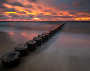 Wall Mural - minimalist landscape showing sea waves and a breakwater at sunset