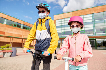 Canvas Print - education, childhood and people concept - school children in face protective medical mask for protection from virus disease riding scooters outdoors