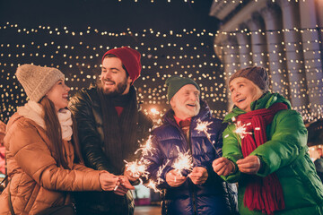 Wall Mural - Photo of full family four members x-mas meeting gathering hold stick fires cheerful positive laugh wait end of year outerwear hat scarf coat evening street illumination outdoors outside