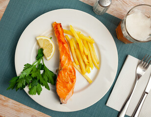 Appetizing salmon steak with vegetables side dish of crispy fries..