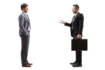 Sticker - Full length profile shot of a businessman in a suit with a briefcase talking to a man