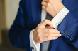 Groom or businessman fasten cufflink on the cuff of the shirt wearing blue suit