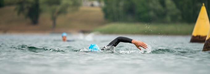 Wall Mural - An athlete in a wetsuit swimming in open water