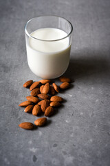 Almond milk in a glass with almond ingredients on table