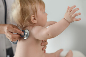 Canvas Print - Pediatrician examining baby with stethoscope in hospital, closeup. Health care