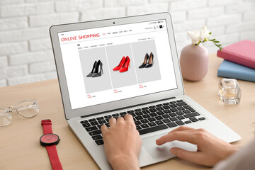 Woman shopping online using laptop at table, closeup