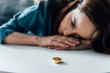 selective focus of depressed woman looking at coffee table with golden ring, divorce concept