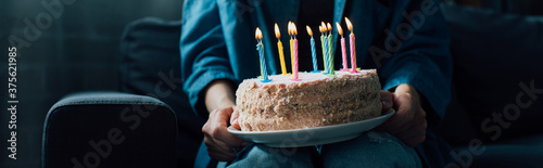 panoramic crop of woman holding birthday cake with candles