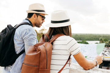 Wall Mural - Happy tourist couple using the map. Travel and love concept in Latin America