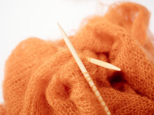 Knitting Needles And Orange Yarn On White Background