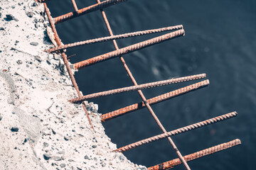 Rusty iron pins protrude from the concrete blocks of collapsing bridge from old age.