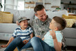 © JustLife - Happy soldier sitting on the floor with his family. Soldier enjoying at home with children..