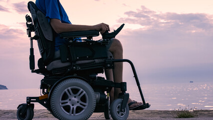 Wall Mural - Man on wheelchair near sea at sunset.