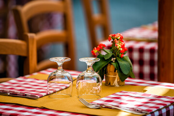 Closeup of two glasses glass upside down on restaurant table in Rome, Italy, Italian cafe outside in traditional style with red and white checkered pattern