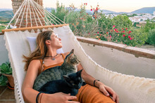 Young Hispanic Woman Resting In Hammock With Her Cat
