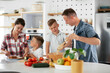 © JustLife - Mother and father making breakfast with sons. Young family preparing delicious food in kitchen.