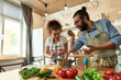 © Svitlana - Italian man adding pepper, spice to the soup while woman stirring it and smiling, couple preparing a meal together in the kitchen