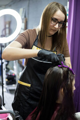 Wall Mural - A hairdresser girl does her hair for her client in a beauty salon