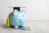 Fototapeta  - Piggy bank with graduation hat and money on table. Tuition fees concept