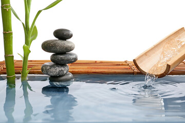 Stack of spa stones and bamboo in water on white background