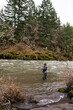 © Kate Daigneault/Stocksy - Man stands in the river casting an orange fly fishing line.