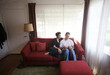 © Dina Marie Photography/Stocksy - Couple on couch in living room holding newborn baby