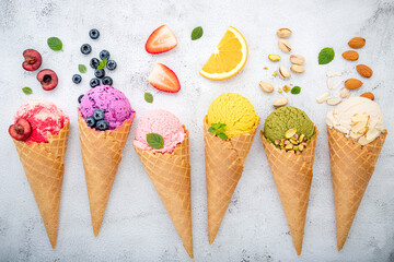 Fototapete - Various of ice cream flavor in cones blueberry ,pistachio ,almond ,orange and cherry setup on white stone background . Summer and Sweet menu concept.