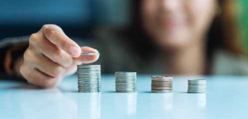 Businesswoman holding and stacking coins on the table for saving money concept