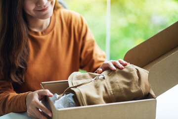 Wall Mural - A woman receiving and opening a postal parcel box of clothing at home for delivery and online shopping concept