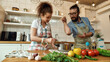 © Svitlana - Italian man adding pepper, spice to the soup while woman stirring it with a spoon. Couple preparing a meal together in the kitchen. Cooking at home, Italian cuisine