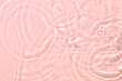 Closeup of pink transparent clear calm water surface texture with splashes and bubbles. Trendy abstract summer nature background. Coral colored waves in sunlight. Copy space.