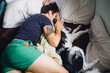 © J Danielle Photography/Stocksy - A man playing and cuddling in bed with an Australian Shepherd boarder collie miz