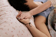 © VegterFoto/Stocksy - Lesbian couple holding hands in bed